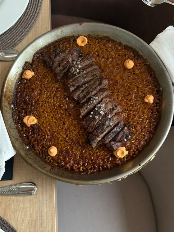 Arroz en paella terminado con láminas de entrecot a la parrilla, visto desde arriba