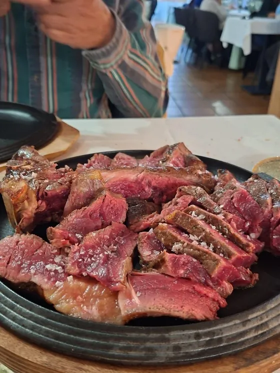 Chuletón a la brasa fileteado, rojo por dentro, en un plato caliente