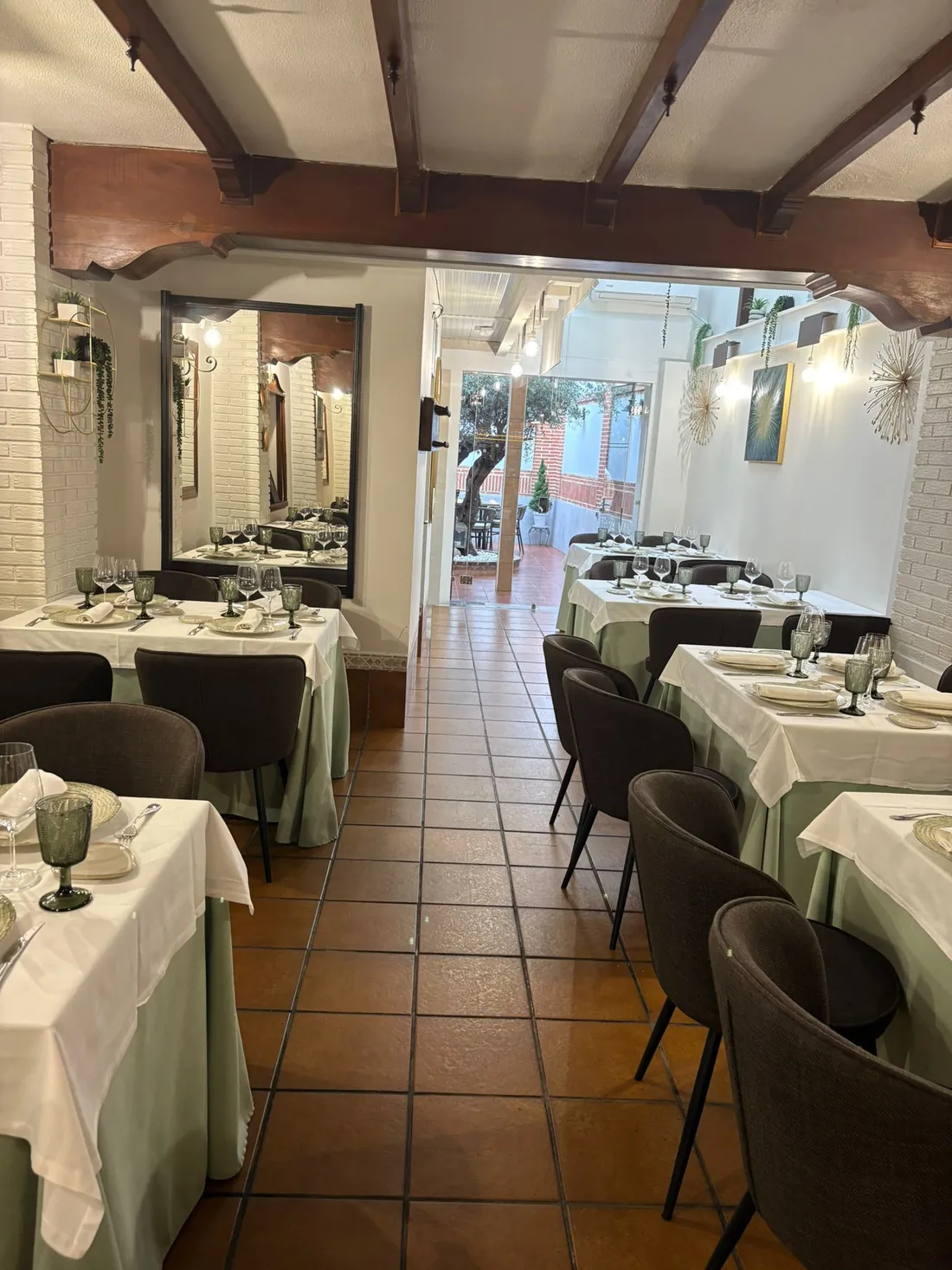El comedor de Redondo, con vigas de madera y mesas con mantel preparadas