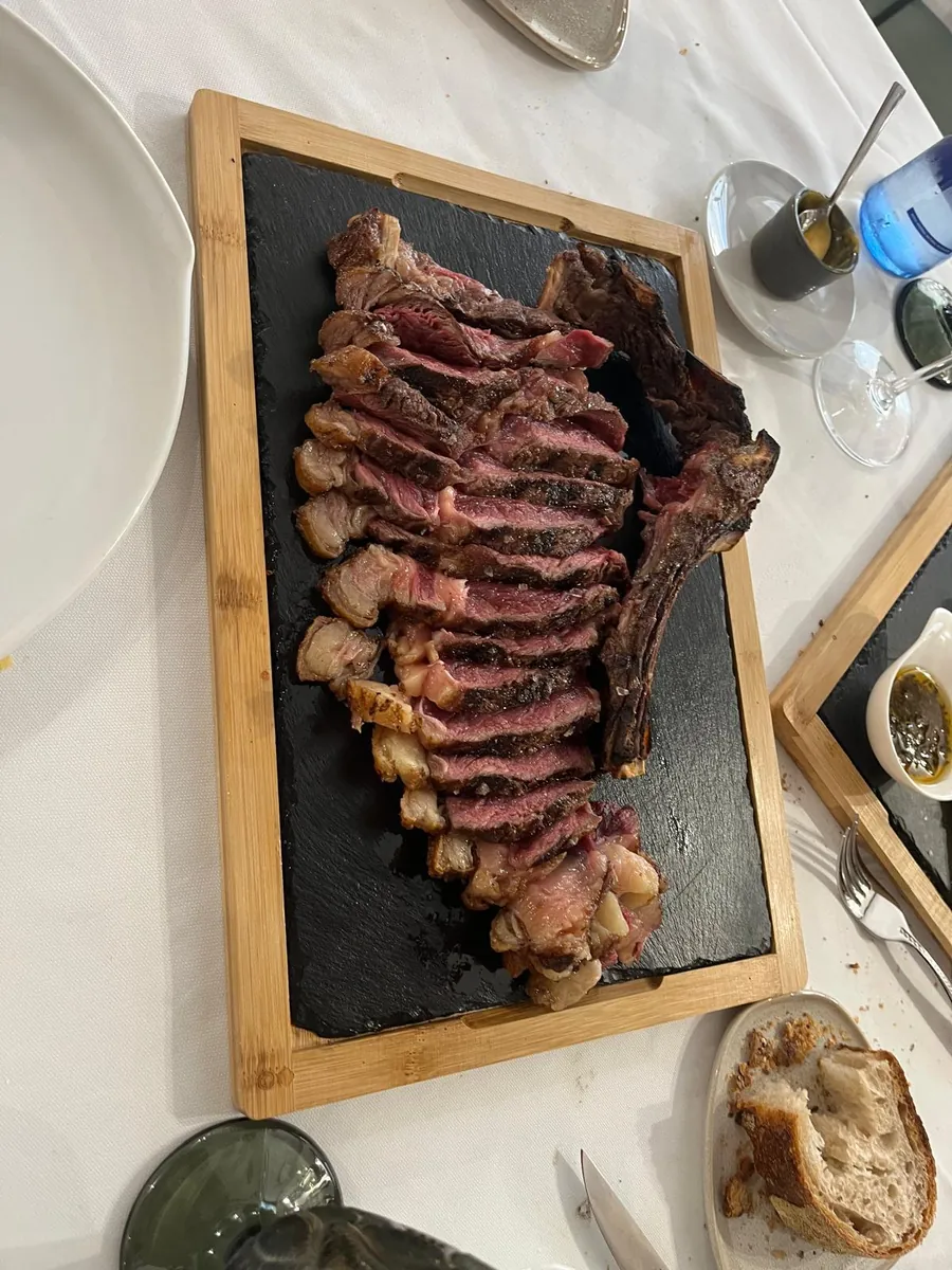 Chuletón a la brasa fileteado sobre una tabla de pizarra