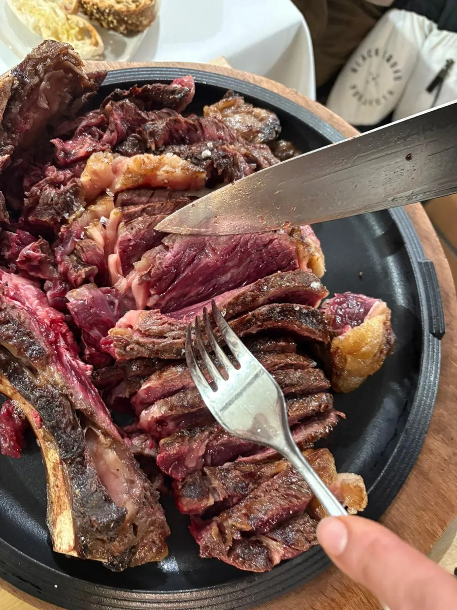 Un chuletón madurado trinchado en la mesa con cuchillo y tenedor