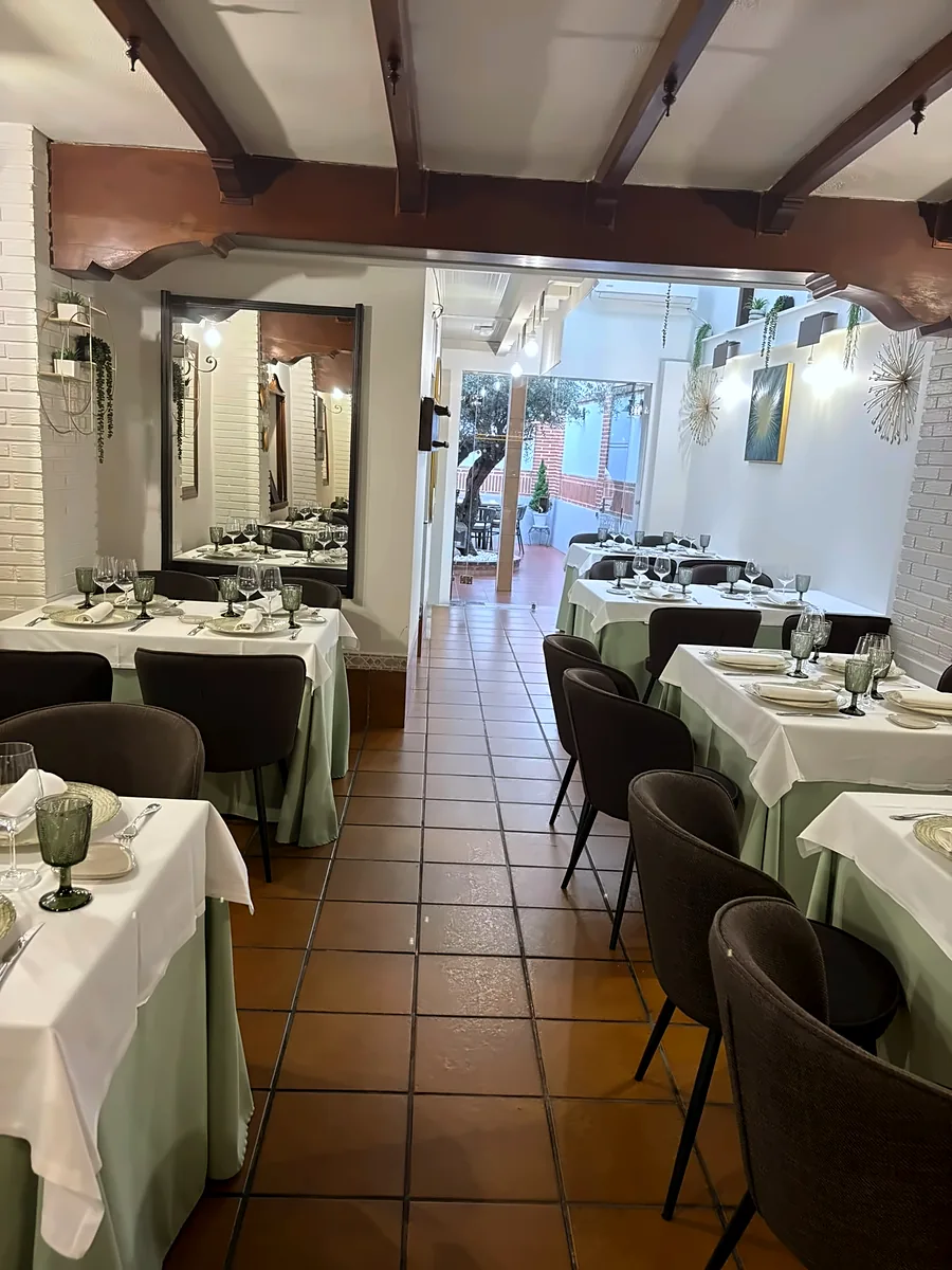 El comedor de Redondo, con vigas de madera y mesas con mantel preparadas