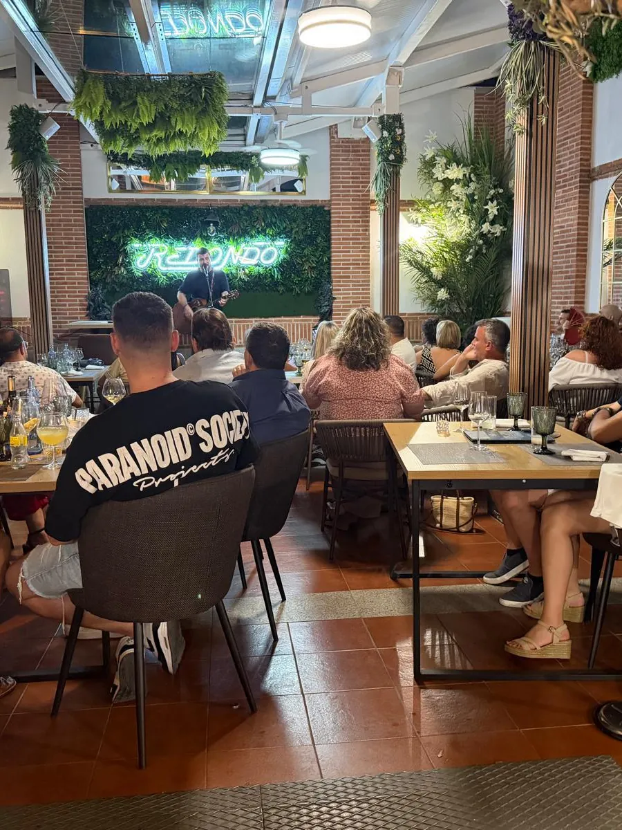 Una sala llena de gente atenta a un espectáculo, con una pantalla al fondo