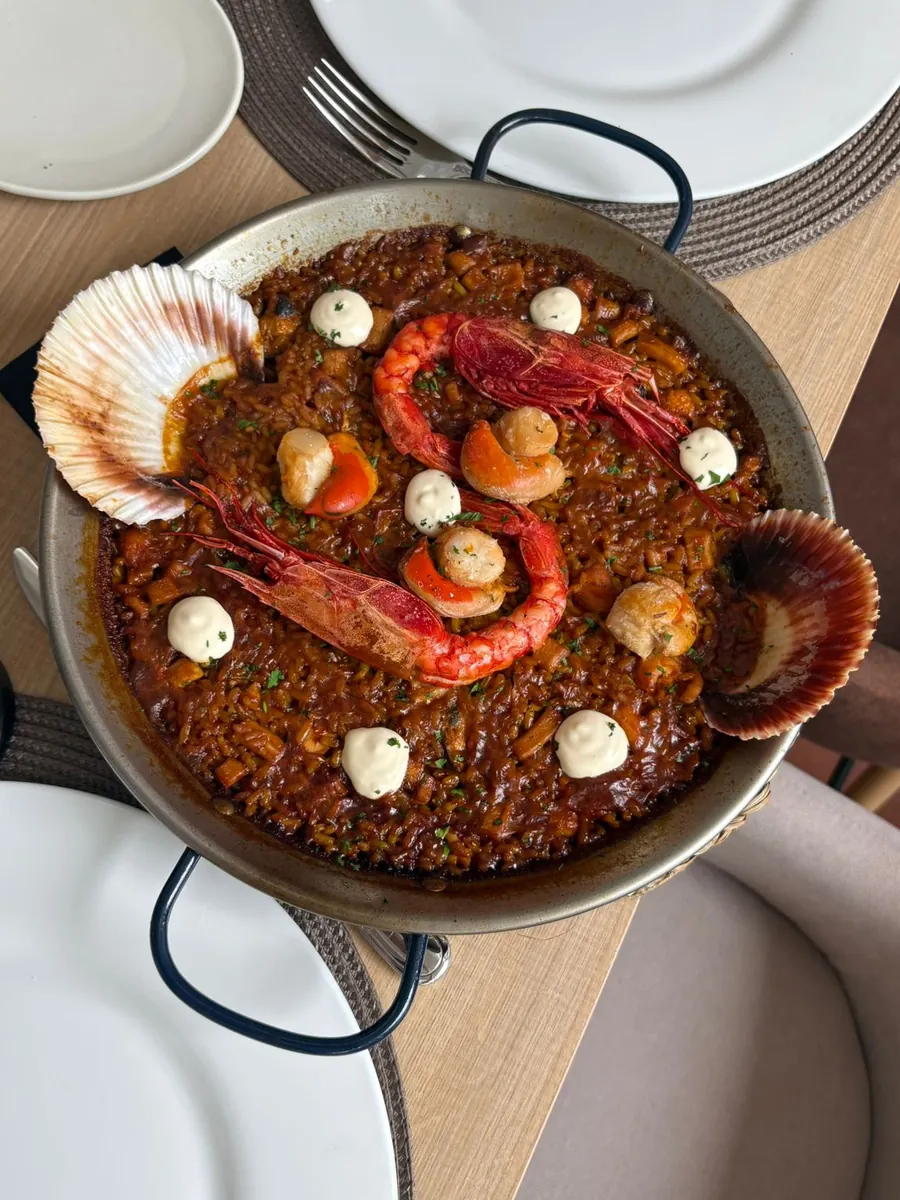 Una paella de marisco con carabineros y conchas, en el centro de la mesa