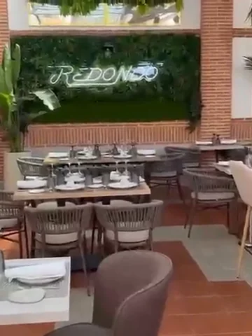La terraza semicubierta con mesas preparadas y plantas